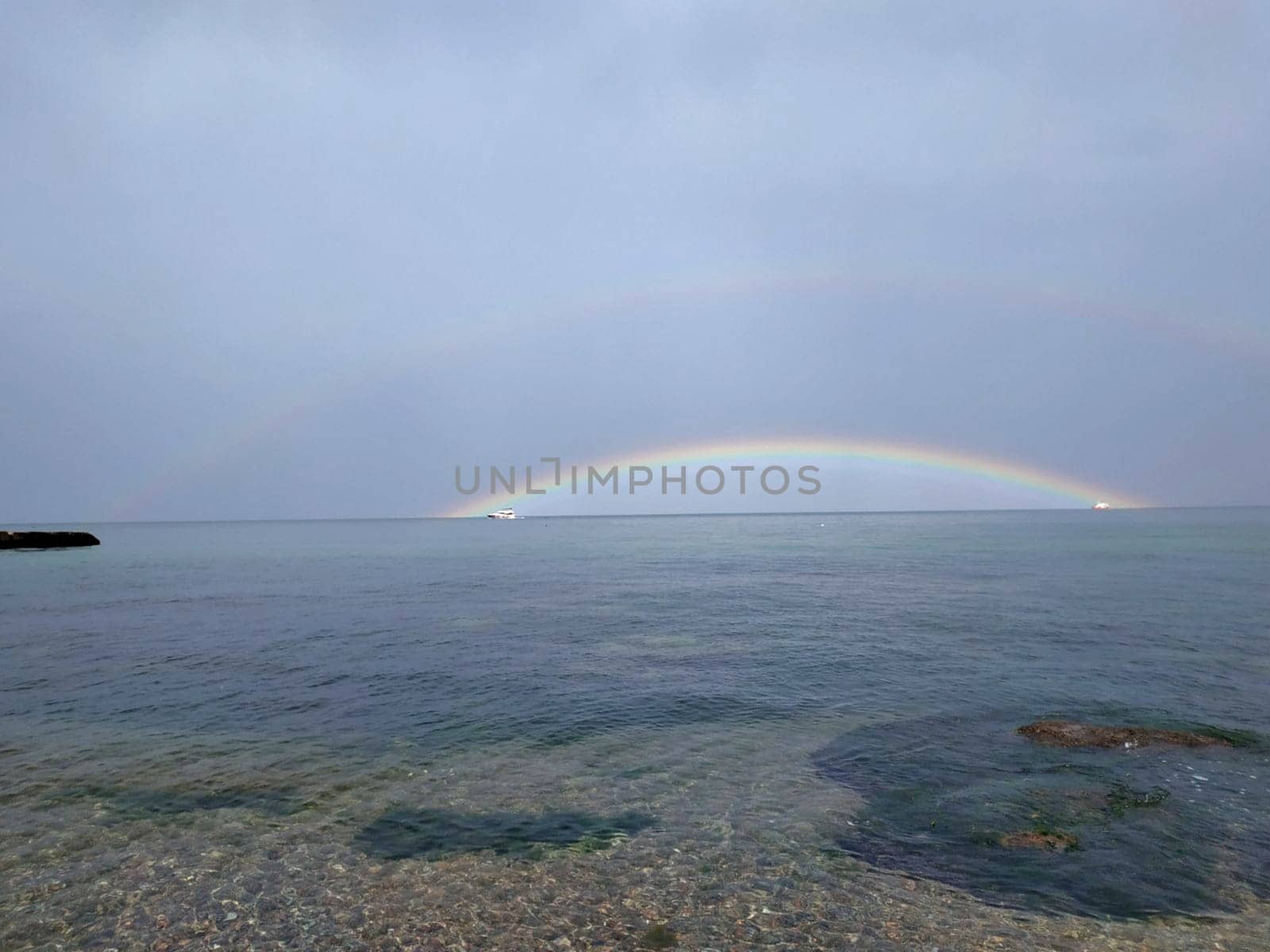 In spring, the water in the Black Sea is clear. A rainbow is visible on the horizon.
