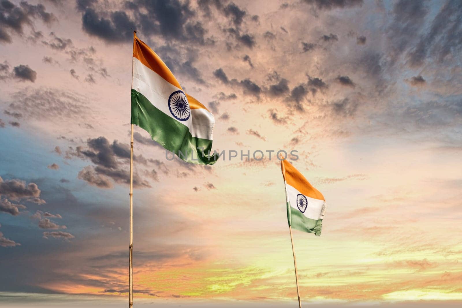 two Indian tri color with saffron green white and ashoka chakra waving in the wind against the blue sky showing the independence and republic day of the world's largest demography India