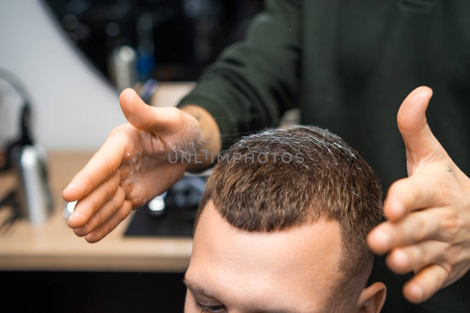 Close up barber hands styling clients hair in barbershop.