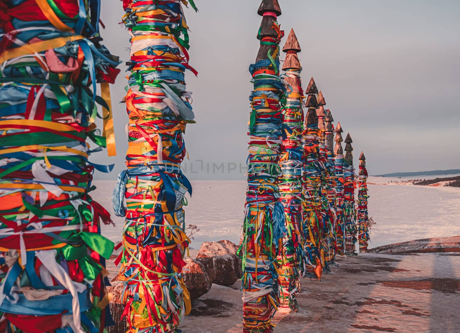 Traditional buryat shaman sacred pillars with colorful ribbons in winter at sunset, cape Burkhan, Olkhon island. Winter Baikal. by Busker