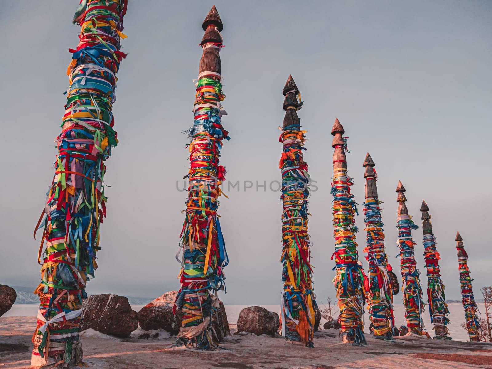 Traditional buryat shaman sacred pillars with colorful ribbons in winter at sunset, cape Burkhan, Olkhon island. Winter Baikal. by Busker