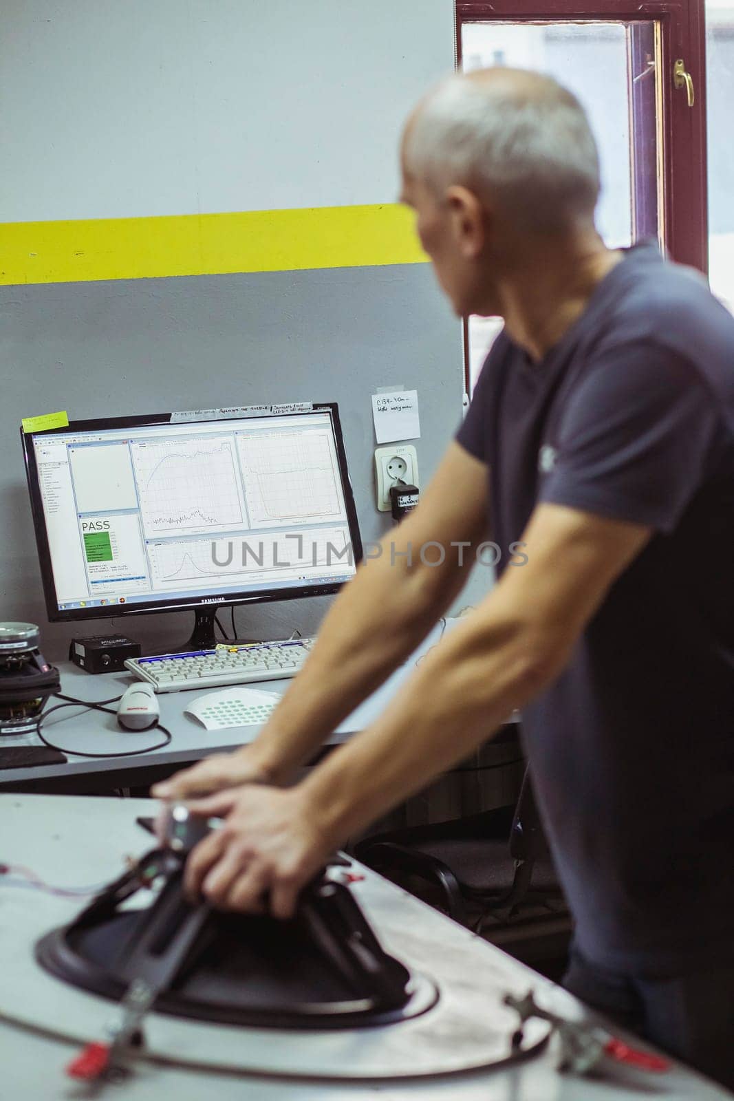 Bila Tserkva, Ukraine, March 9, 2021: Gray-haired worker testing audio speaker at factory