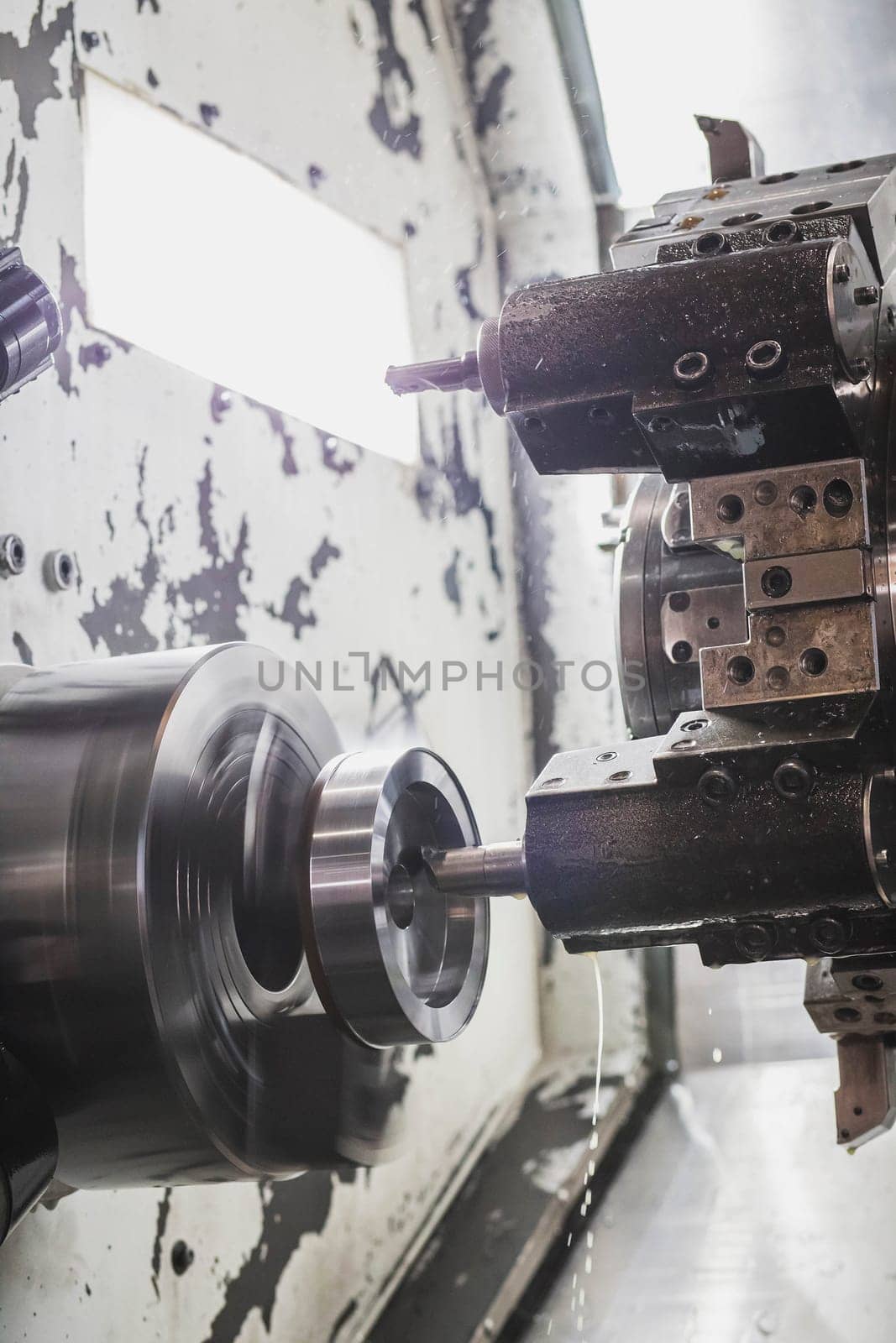 A milling cutter in a CNC machine cuts a metal workpiece that rotates at high speed.
