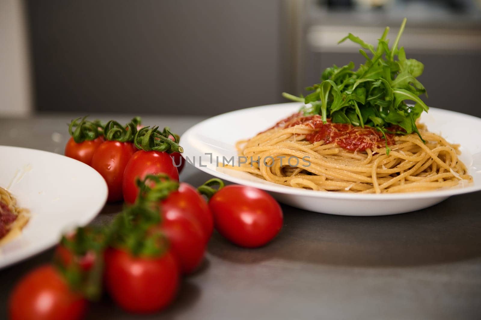 Food background with classic Italian cuisine dish. Pasta spaghetti with tomatoes, arugula leaves and parmesan cheese. Copy advertising space. Classic Italian cuisine dish.