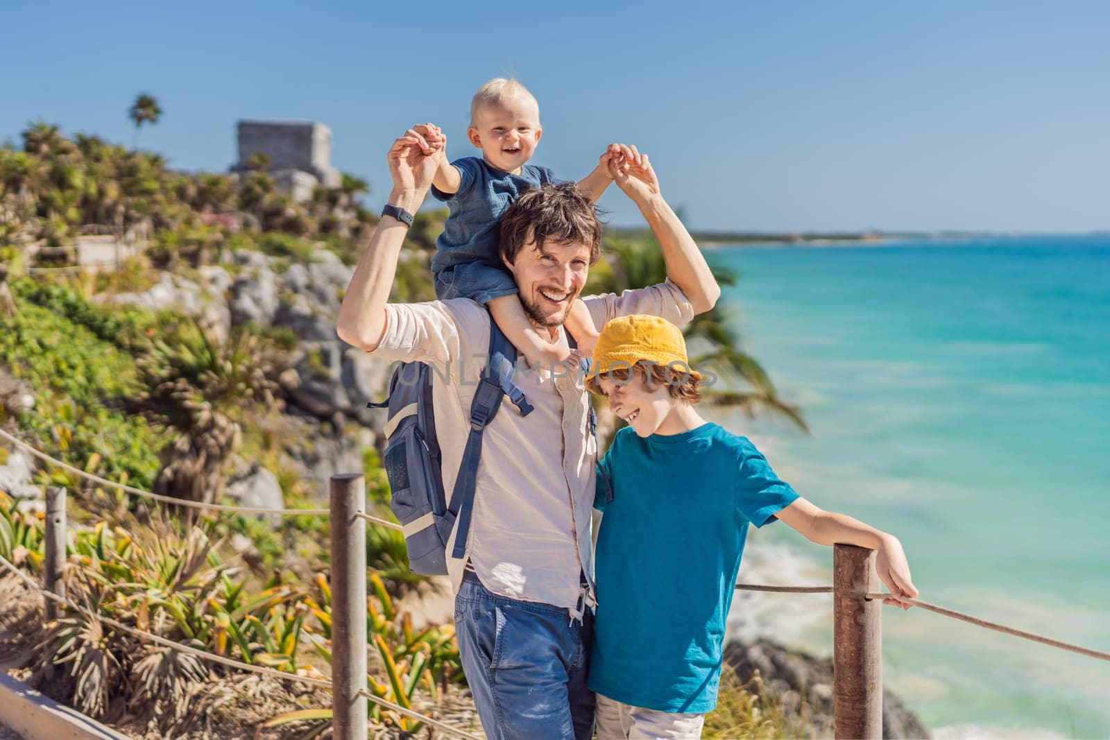 Father and two sons tourists enjoying the view Pre-Columbian Mayan walled city of Tulum, Quintana Roo, Mexico, North America, Tulum, Mexico. El Castillo - castle the Mayan city of Tulum main temple.