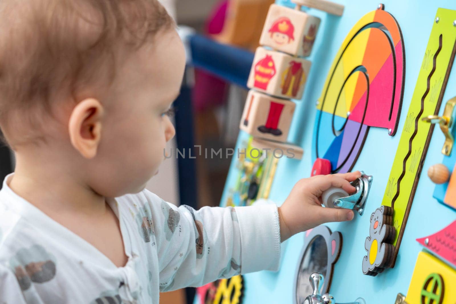 The kid is concentratedly spinning the wheel on the game board.