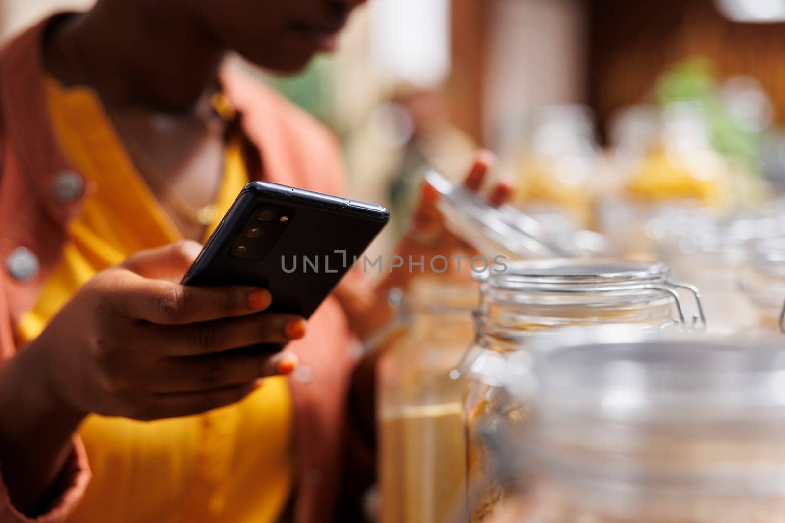 Black woman holds mobile device in store by DCStudio
