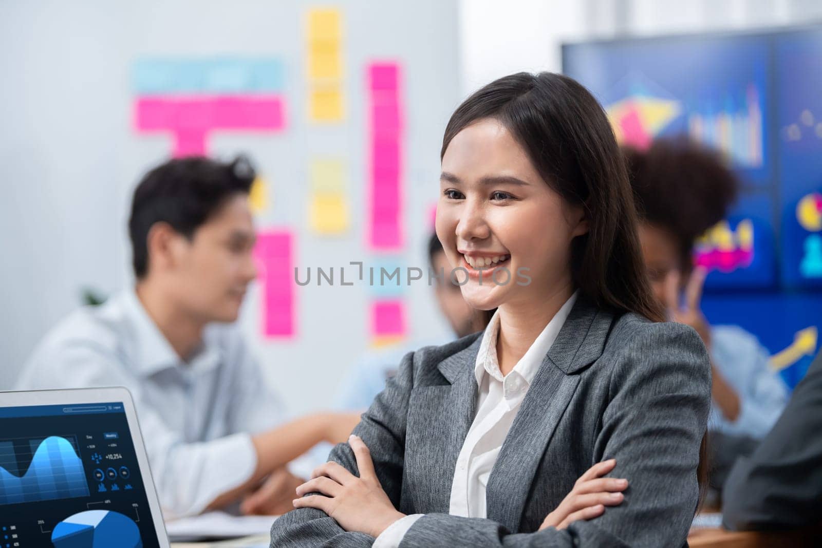 Portrait of happy young asian businesswoman with group of office worker on meeting with screen display business dashboard in background. Confident office lady at team meeting. Concord