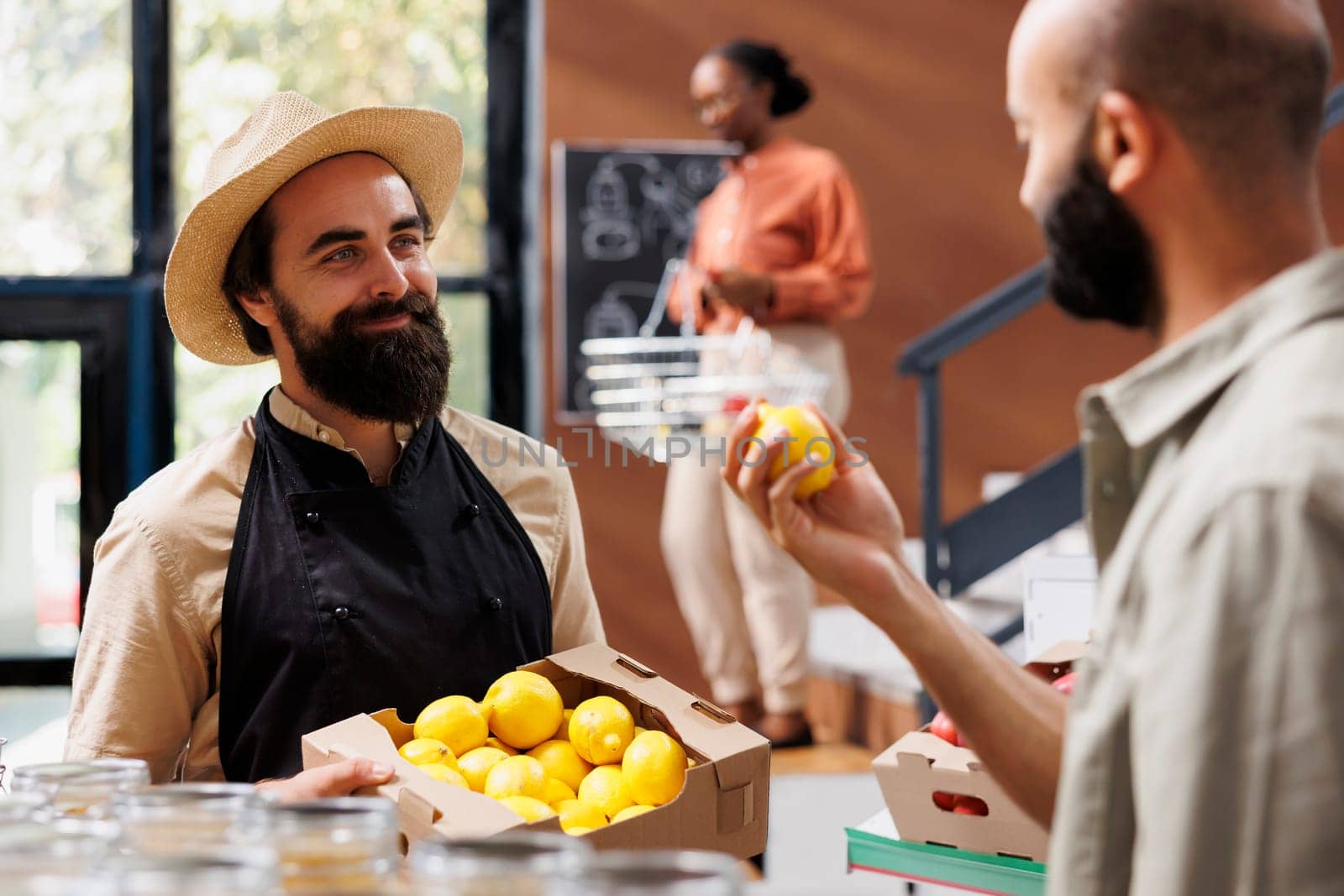 Customer in zero waste supermarket talking with vendor, inquiring about newly received batch of farm grown organic fruits. Environmentally conscious client in bio store asking for fresh lemons.