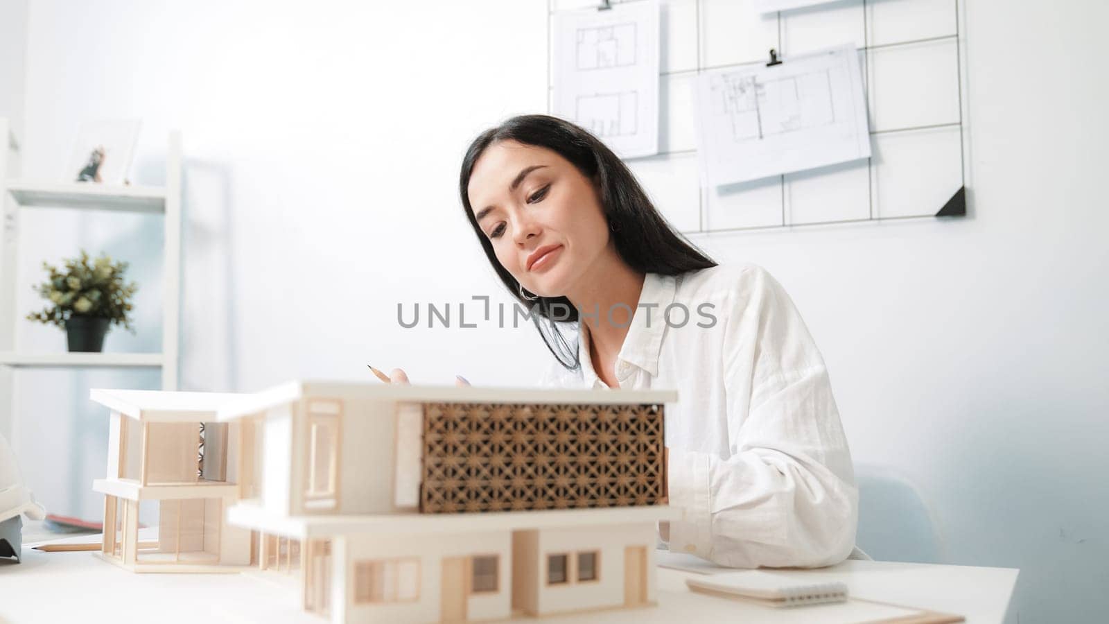 Closeup portrait image of professional young beautiful engineer architect using triangular scale measures house model with focusing at modern office. Business creative design concept. Immaculate.