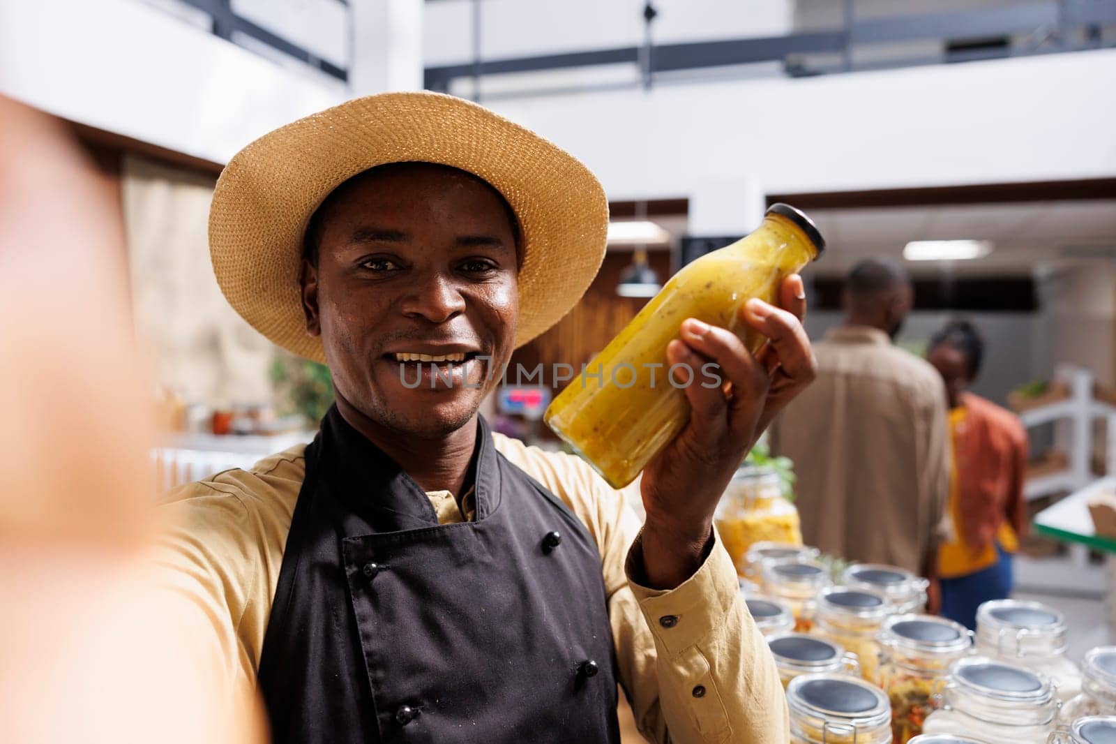 African American business owner promotes fresh, organic products. Filming with smartphone, he showcases eco friendly packaging and glass jars with healthy food. Ideal for advertising.