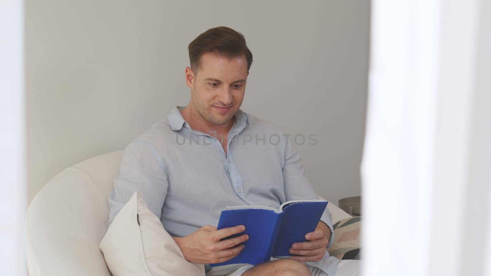 Middle age man sitting on sofa read textbook increase knowledge about social and technology for occupation or raise children to be good adult as smart father. Lifelong learning concept. Divergence.