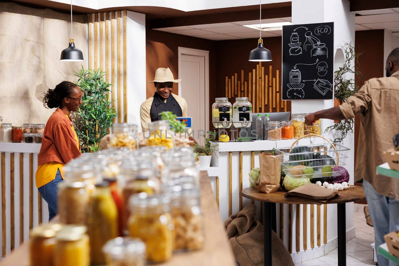 Black business owner helps female client at a local eco friendly supermarket selling fresh, organic food. Reusable packaging, bulk items, and sustainable tools promote a healthy, zero-waste lifestyle.