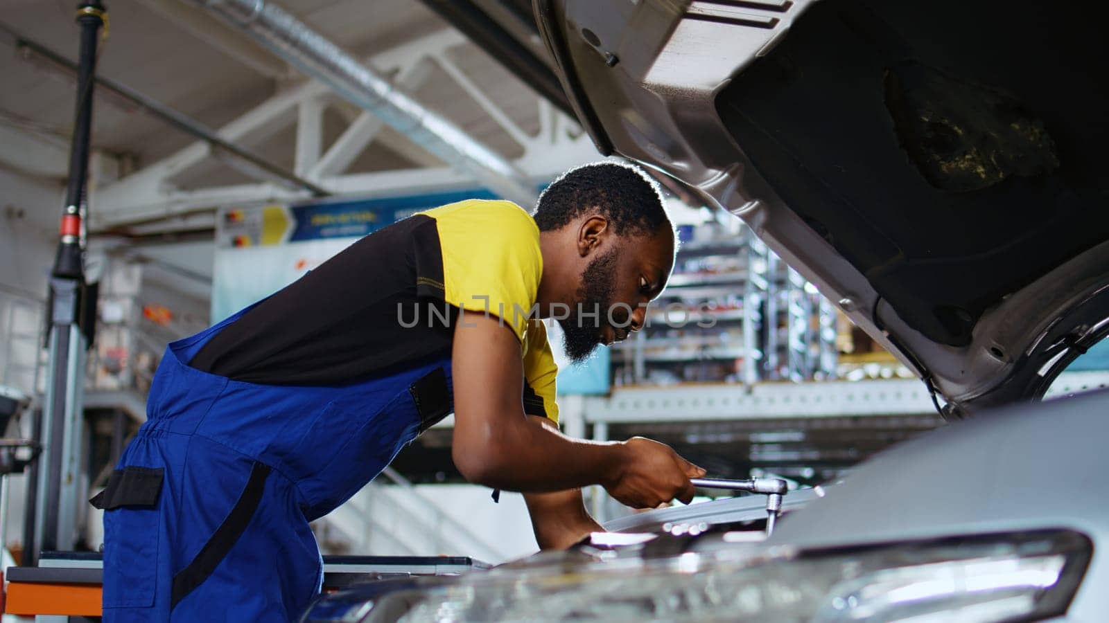 Meticulous specialist in car service picks torque wrench from work station bench, using it to tighten screws after replacing engine. Professional in garage fixing client automobile, close up shot