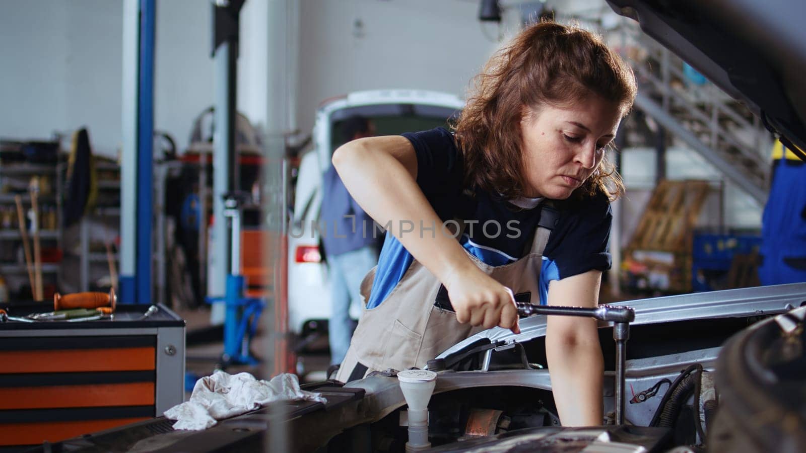 Precise worker in car service using torque wrench to tighten bolts after checking vehicle performance during checkup. Expert using professional tool in garage to repair and clean automobile