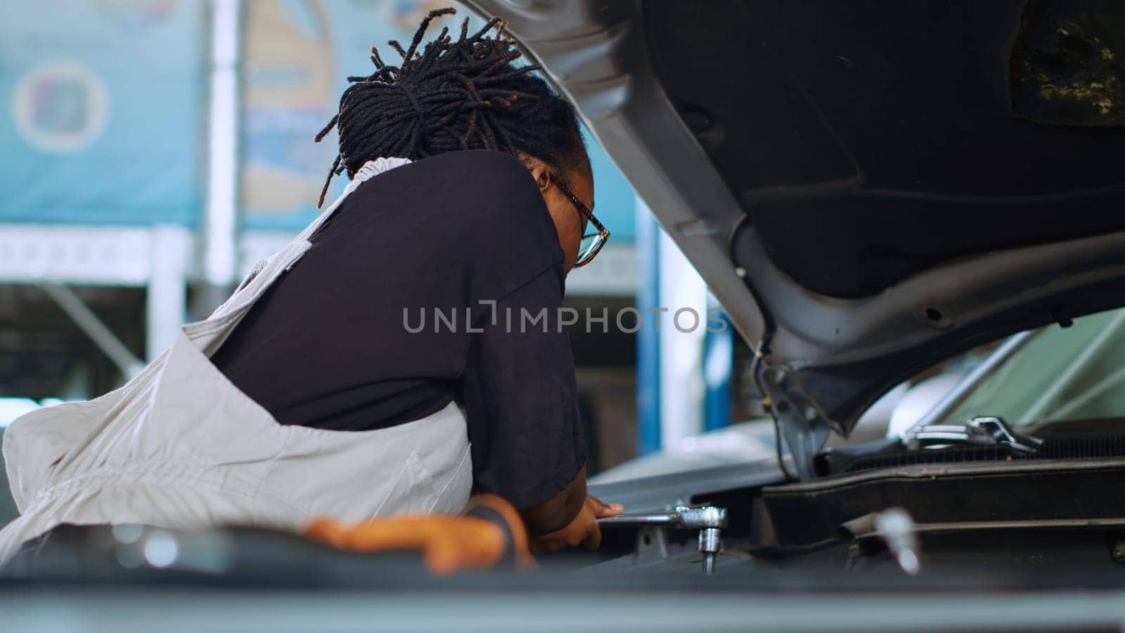 Experienced mechanic in garage using torque wrench to tighten nuts inside opened up vehicle, preparing to change oil. Auto repair shop worker doing checkup on car to prevent damages, close up shot