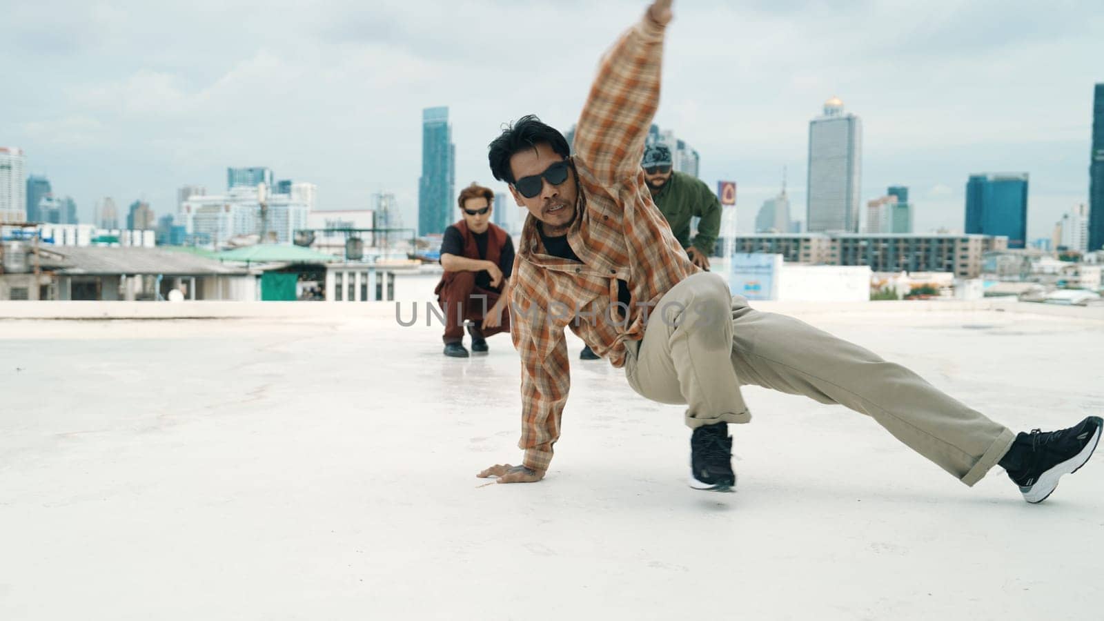 Professional hispanic break dancer practice B boy dance while multicultural friends at roof top. Young modern dancing group doing hip hop movement. Style,fashion,action. Outdoor sport 2024. Endeavor.