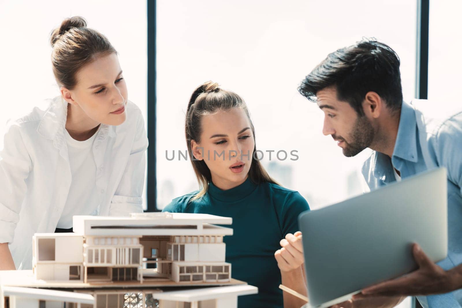 Portrait of skilled architect holding laptop while present idea to engineer team. Group of businesspeople brainstorm and analysis building construction. Civil engineering, working together. Tracery.