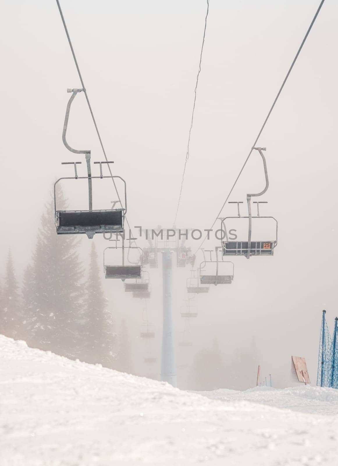 Empty ski lifts during a foggy morning at a snow-covered mountain resort by Busker