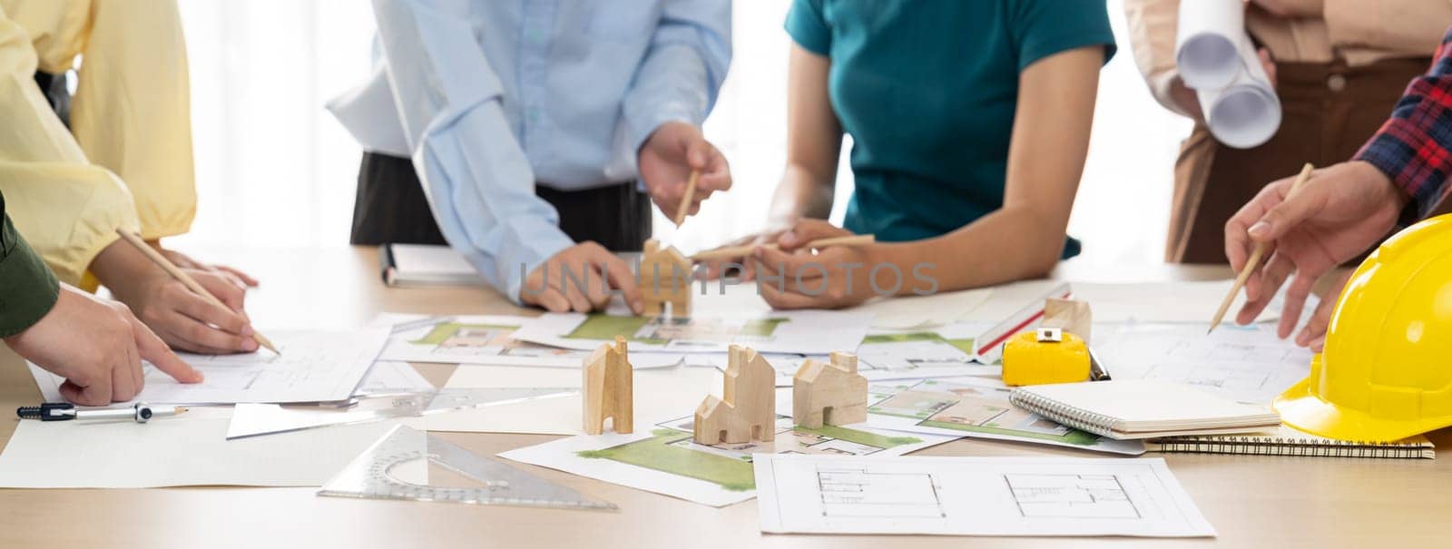 Professional architect team plans to build eco house at meeting table with green design document and architectural equipment scatter around. Living and design concept. Closeup. Delineation.