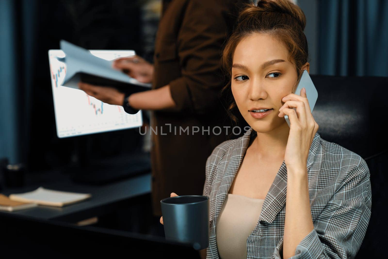 Businesswoman calling with customers to make new project job at modern office while coworker checking paperwork folder of business plan to database report meeting at over late night time. Infobahn.