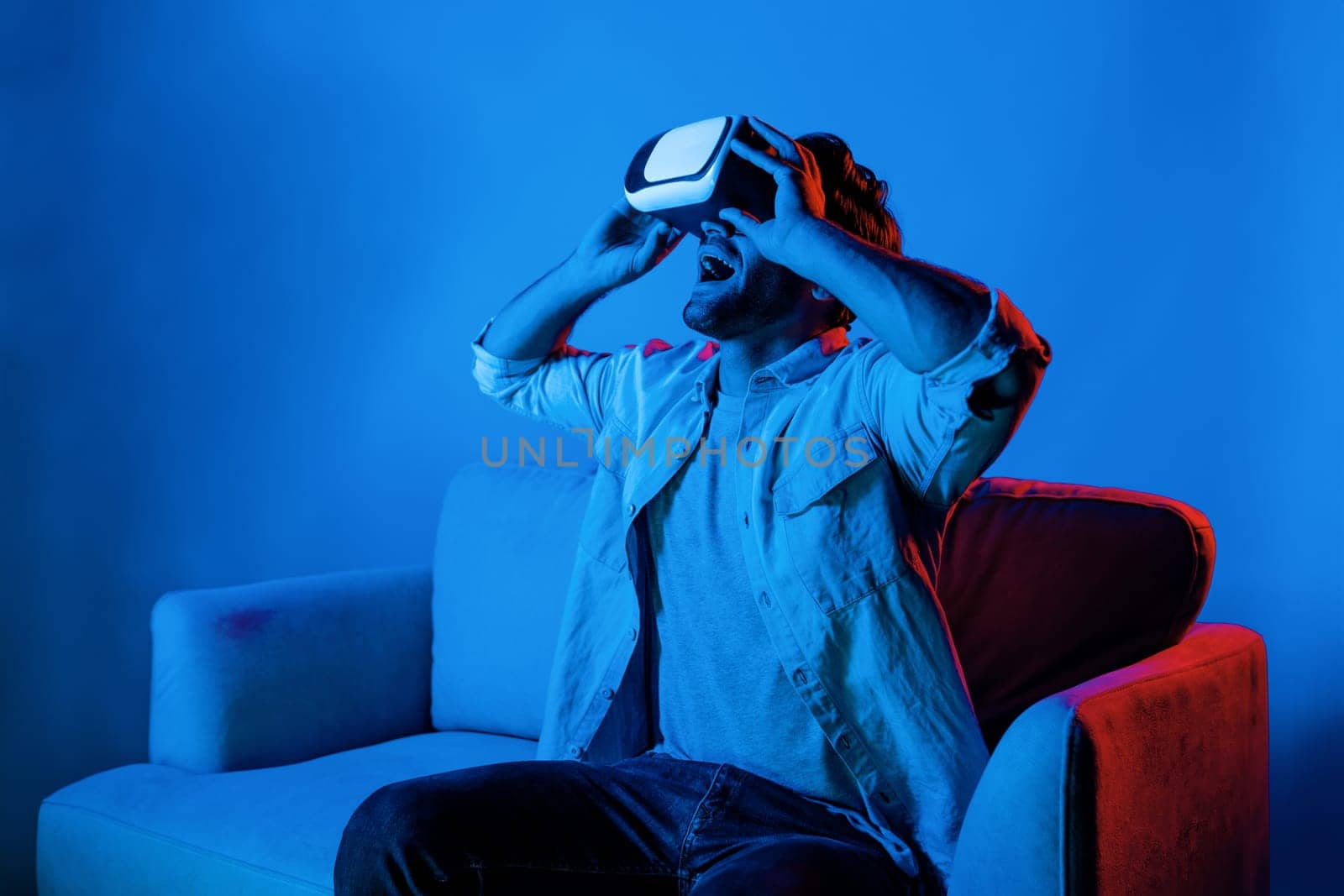 Happy man sitting at sofa while wearing VR goggle to watch movie. Deviation. by biancoblue