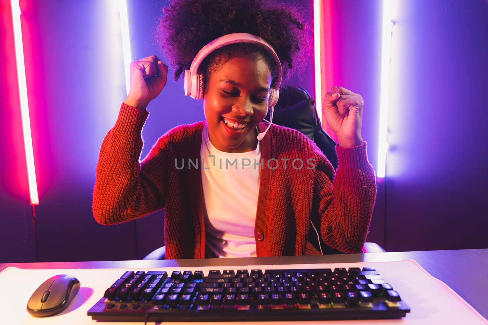 Gaming streamer, African girl playing online fighting with Esport skilled team wearing headphones in neon color lighting room. Talking other players planing strategies to win competitors. Tastemaker.