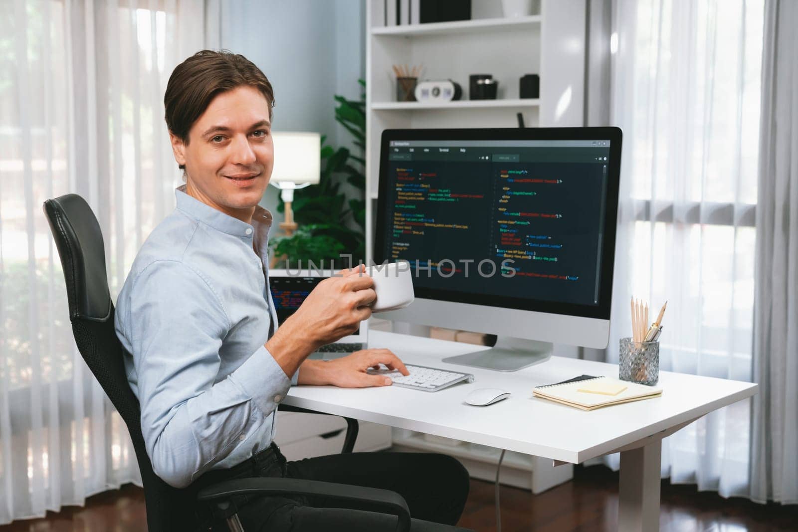 IT developer looking camera with holding coffee cup with online software on pc and laptop monitor beside, coding program on updated version application project creating new code system. Pecuniary.