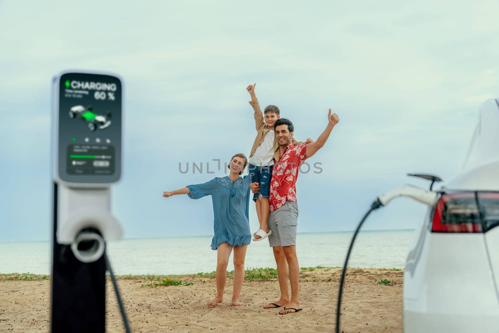 Family vacation trip traveling by the beach with eco-friendly electric car, lovely and cheerful family charging EV car battery on the seascape with green and sustainable energy. Perpetual