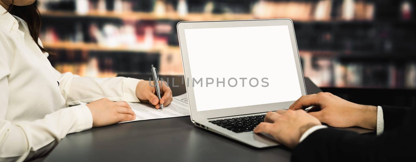 Empty laptop computer screen for savvy design mockup on a table in library by biancoblue