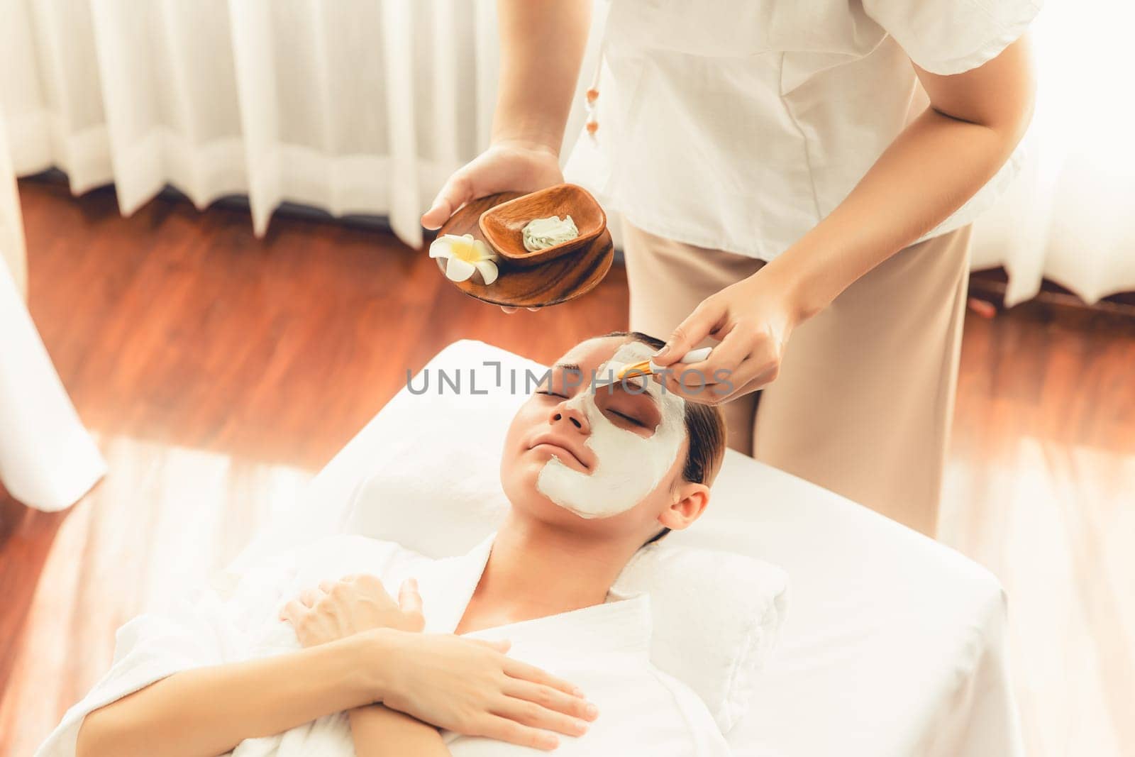 Serene ambiance of spa salon, woman customer indulges in rejuvenating with luxurious face cream massage with modern daylight. Facial skin treatment and beauty care concept. Quiescent