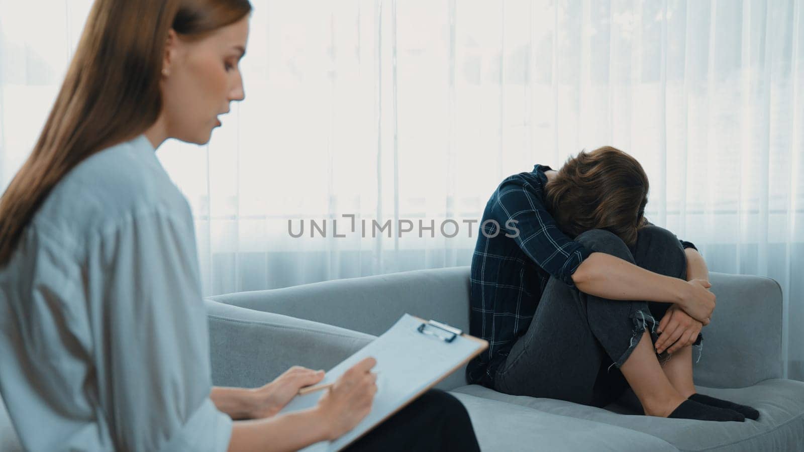 Sad PTSD woman patient in therapy for mental health with psychologist, depression or grief after life failure. Frustrated trauma young woman talking to prim psychologist about emotion in clinic