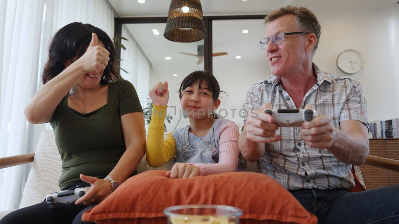 Grandfather, grandmother and granddaughter play console game as hobby. Old senior use technology activity communicate with new generation kid cross generation gap strengthen family bond. Divergence.