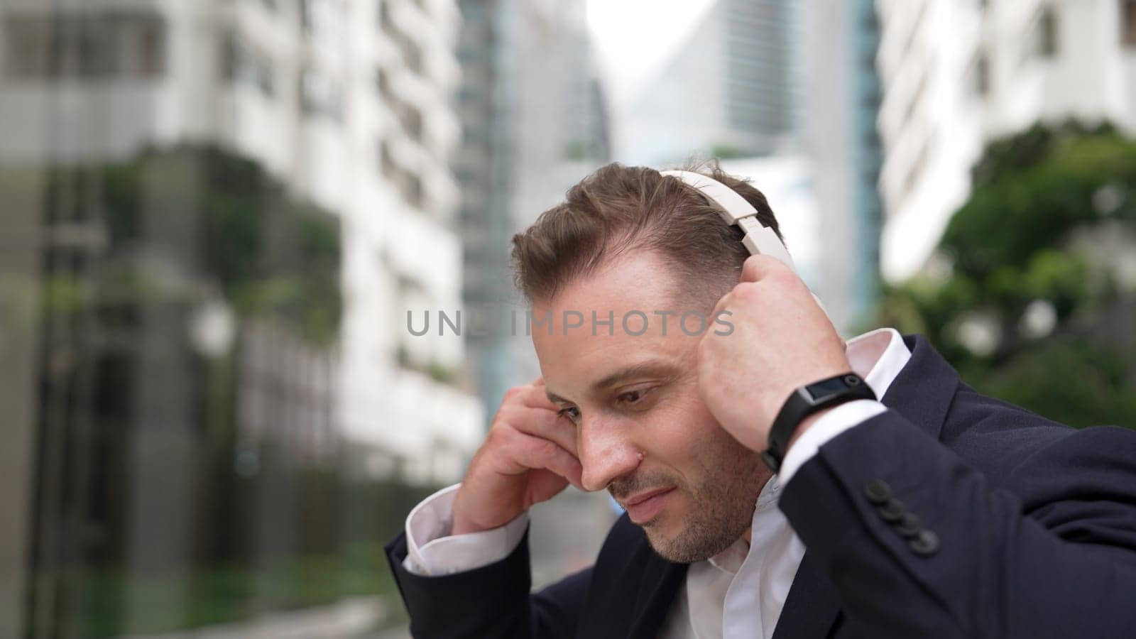 Businessman put on headphone and listen relaxing music while sitting . Urbane. by biancoblue