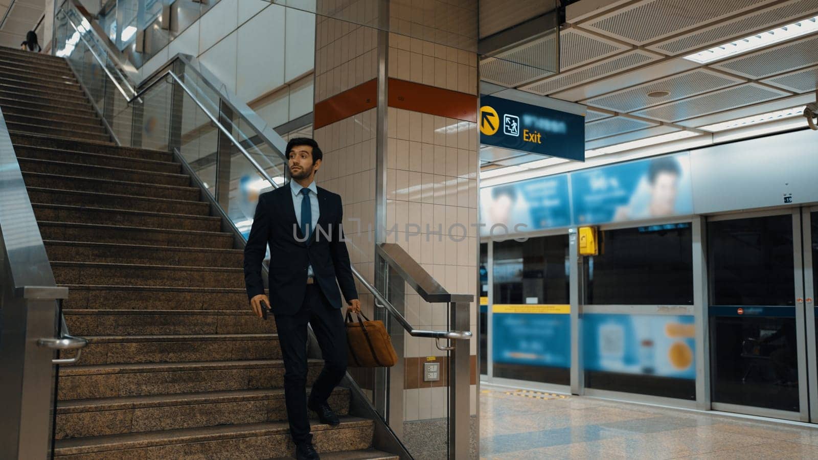 Professional caucasian business man walking down stair to subway or sky train while going to workplace. Skilled project manager using public transport while wearing formal suit. Rush hour. Exultant.