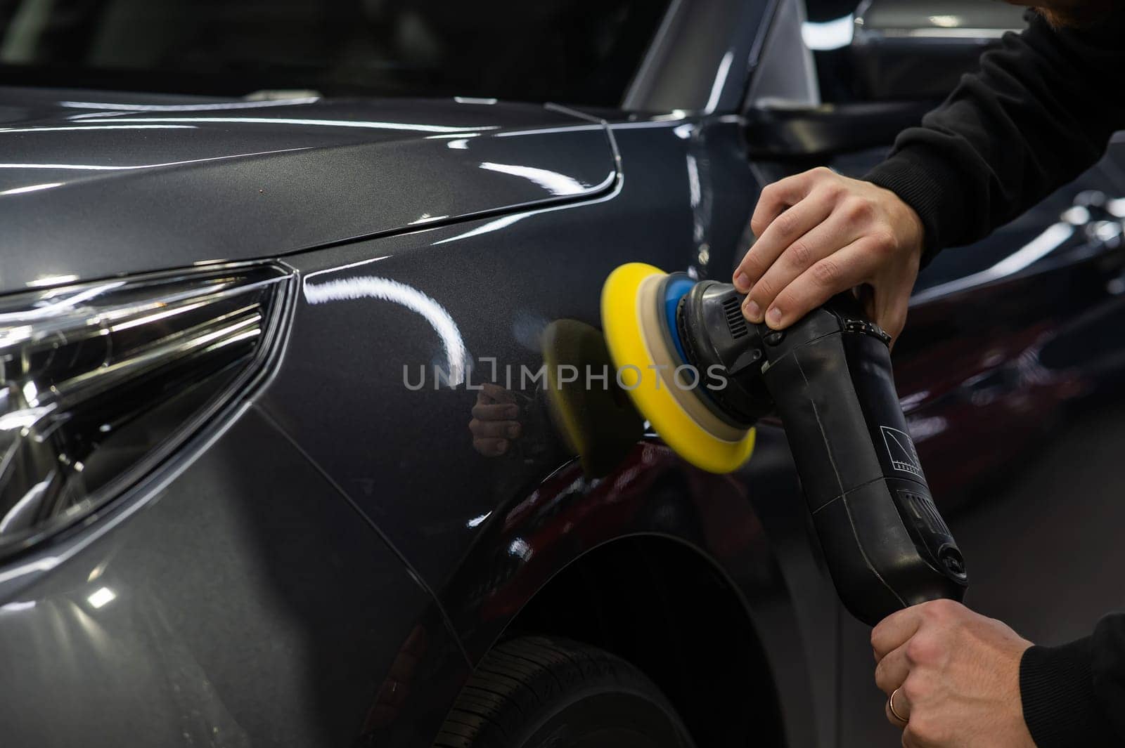 A master polishes the surface of a car body