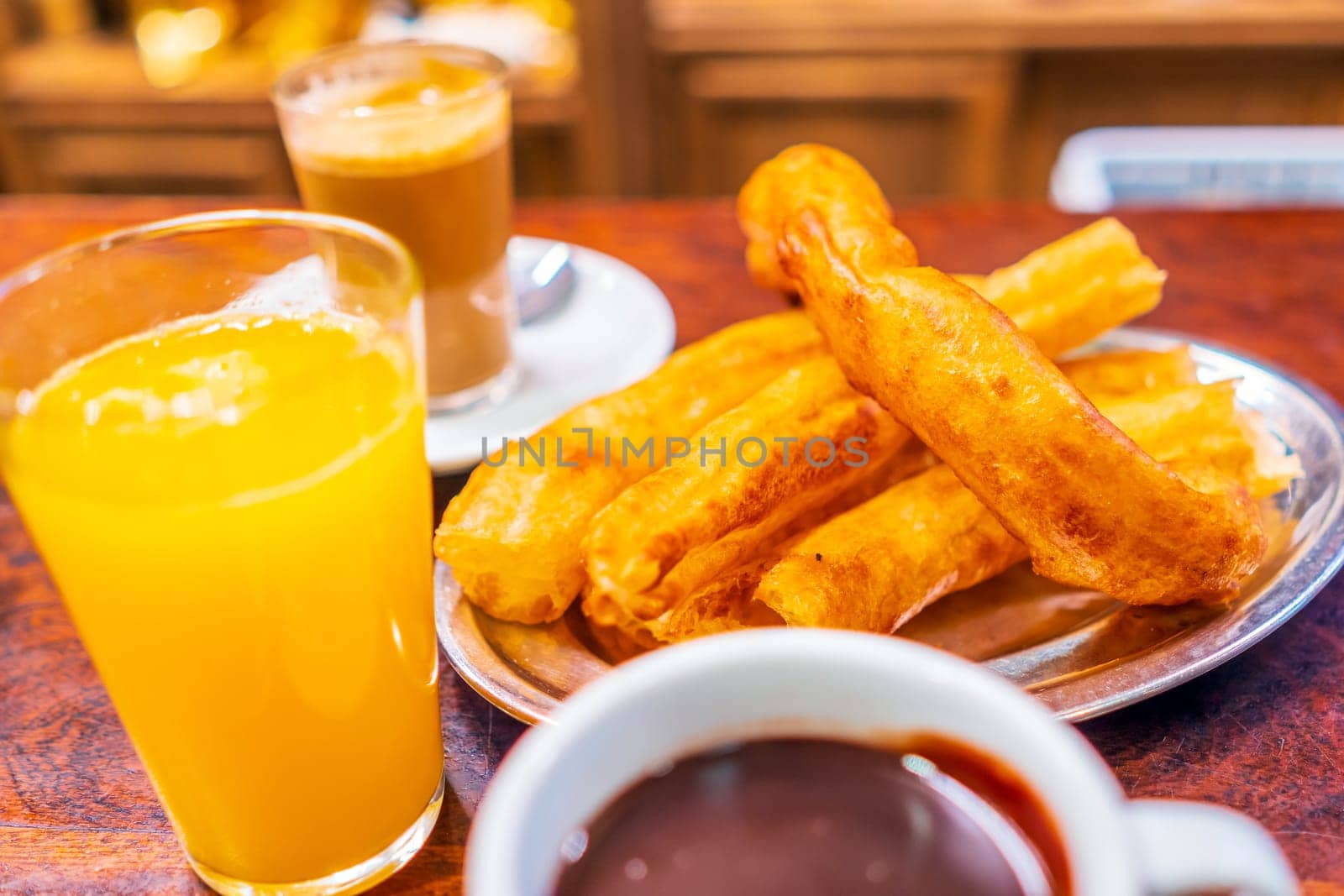 Typical Spanish breakfest snack churros served with cup of hot chocolate, orange juice and coffee in Seville, Spain