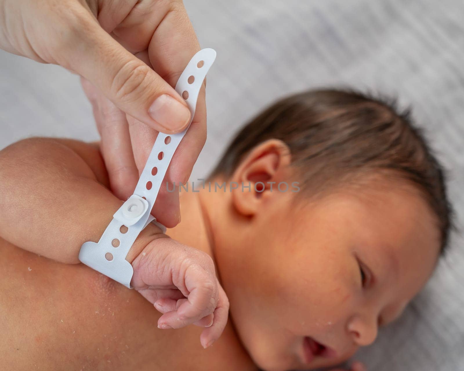 Woman holding newborn by tag on hand