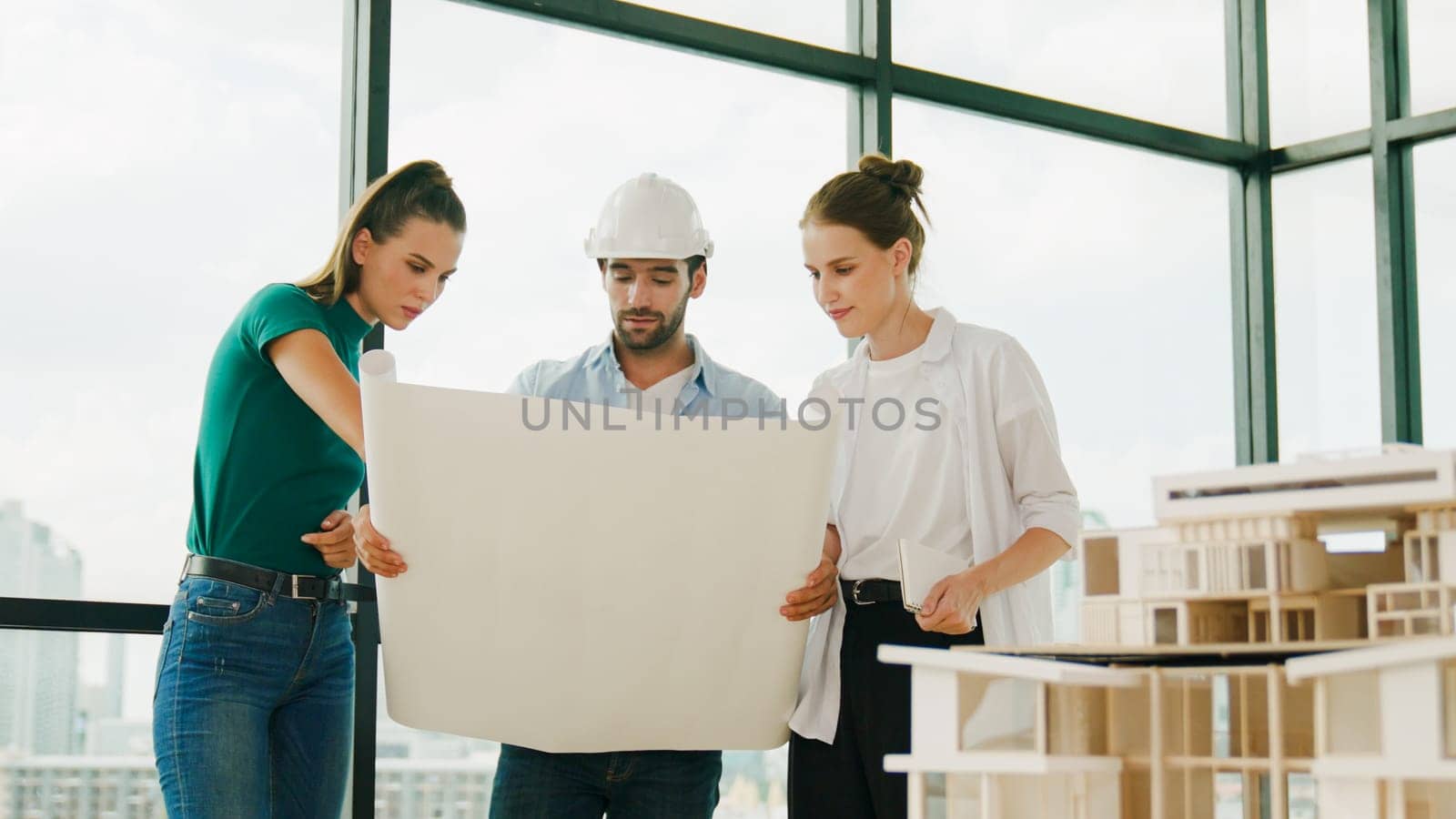 Professional architect engineer team talking, sharing, brainstorming about design while manager hold at project plan. Young architect holding plan while manager listen and point at plan. Tracery