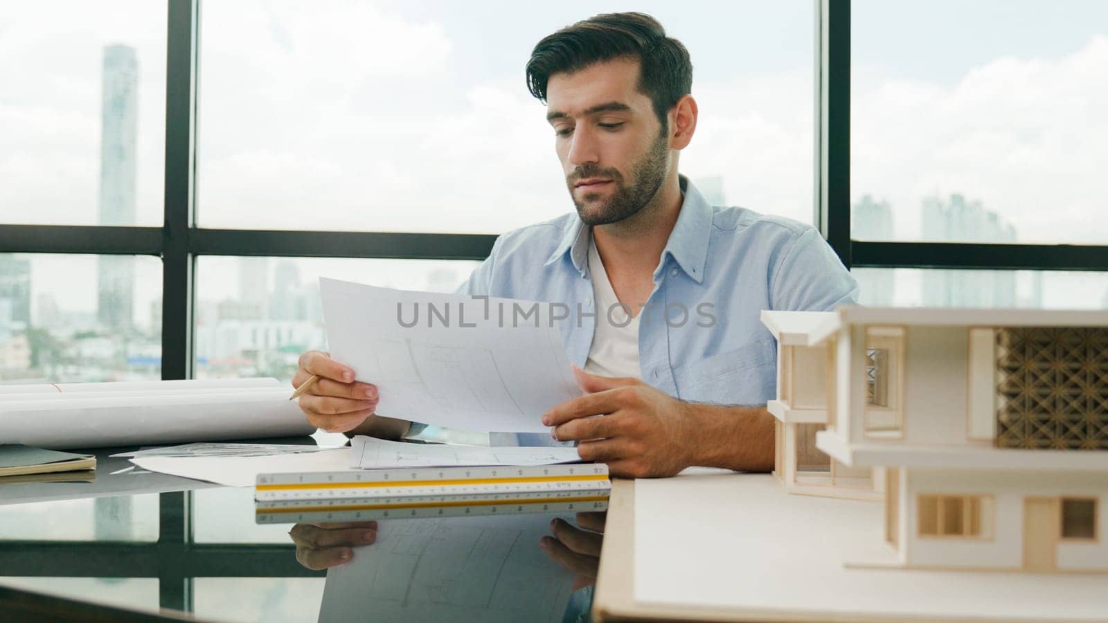 Skilled smart architect engineer writing house construction on blueprint at table with house model, architectural equipment, Interior designer draw, draft, plan building design at office. Disputation