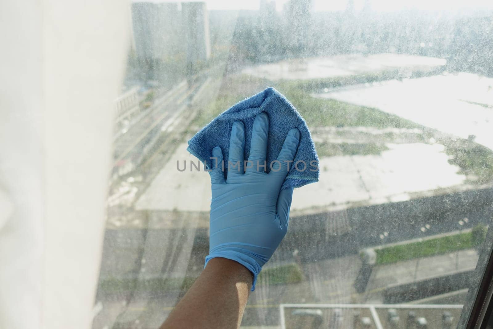 close up of person hand in gloves cleaning window glass .