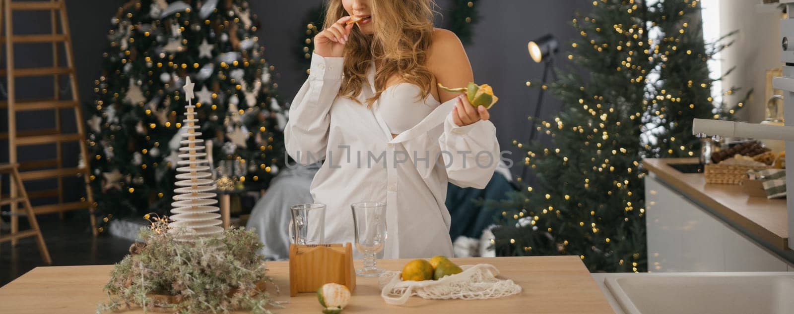 Woman Kitchen Christmas decor in white shirt, peeling tangerines. Illustrating New Year's mood holiday preparations.