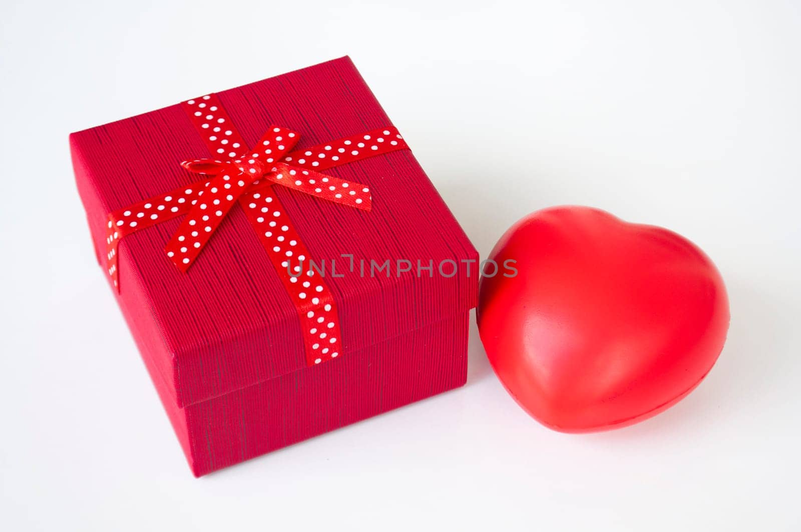 Red present with heart shape on white background with customizable space for text. Copy space.