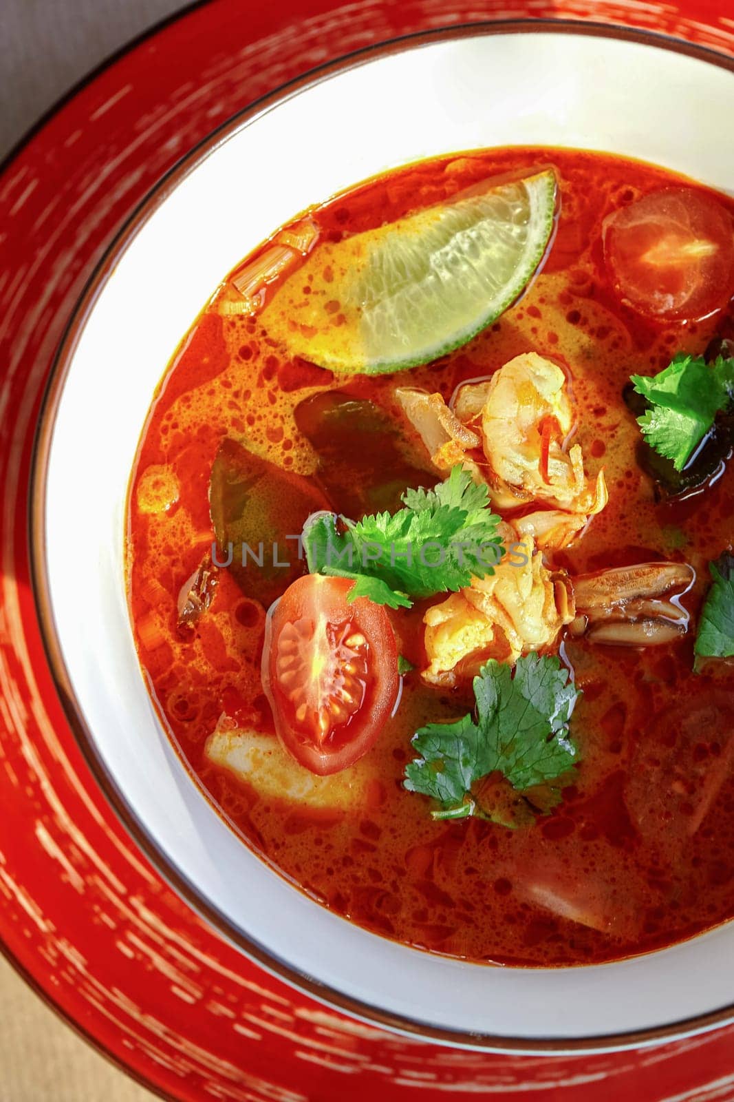 Rich Thai Tom Yum soup with shrimp, squid, mushrooms, tomatoes, and lime by nazarovsergey