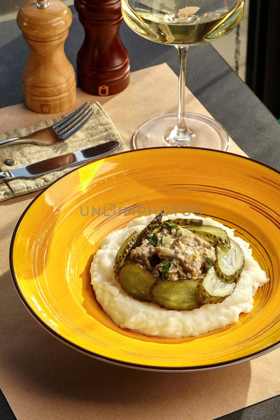 Beef stroganoff with mashed potatoes and pickles on yellow plate by nazarovsergey