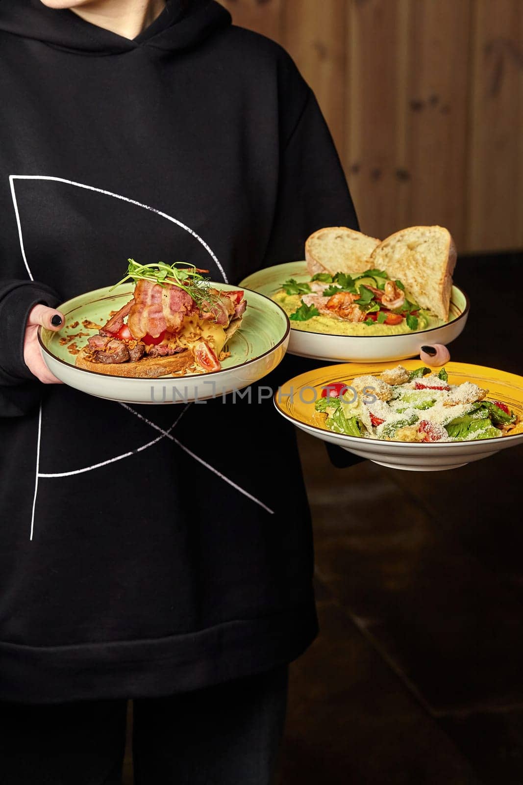 Waitress balancing plates of bruschetta, shrimp hummus, and Caesar salad by nazarovsergey