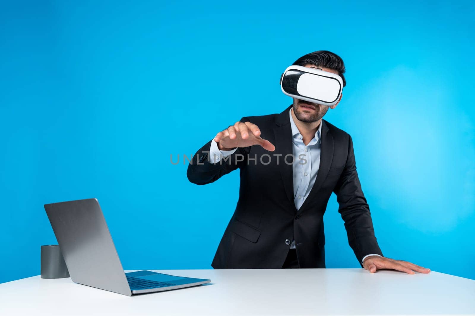Professional project manager looking by using VR goggle while sitting at laptop. Skilled business man wearing visual reality headset while connecting metaverse or visual world. Innovation. Deviation.