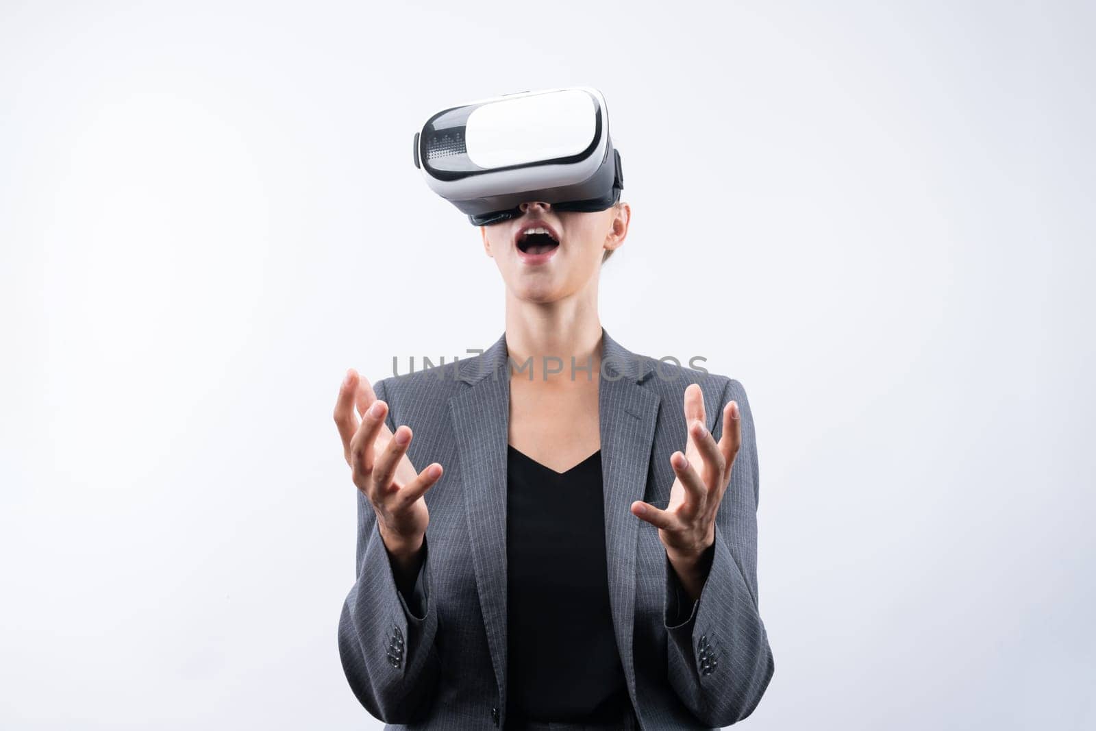 Business woman holding something while wearing VR goggle and standing at white background. Project manager with headset enter visual reality world program by using technology innovation. Contraption.