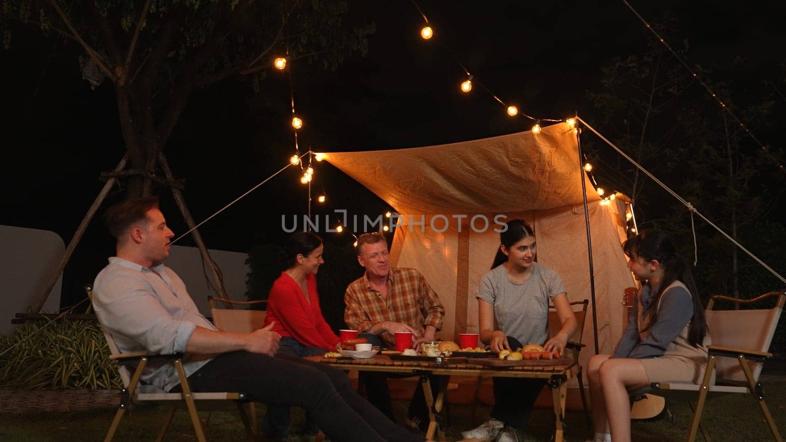 Family gather for holiday celebration in garden. Family member gather have dinner. Outdoor camping activity to relax with food and spend time with younger generation cross generation gap. Divergence.