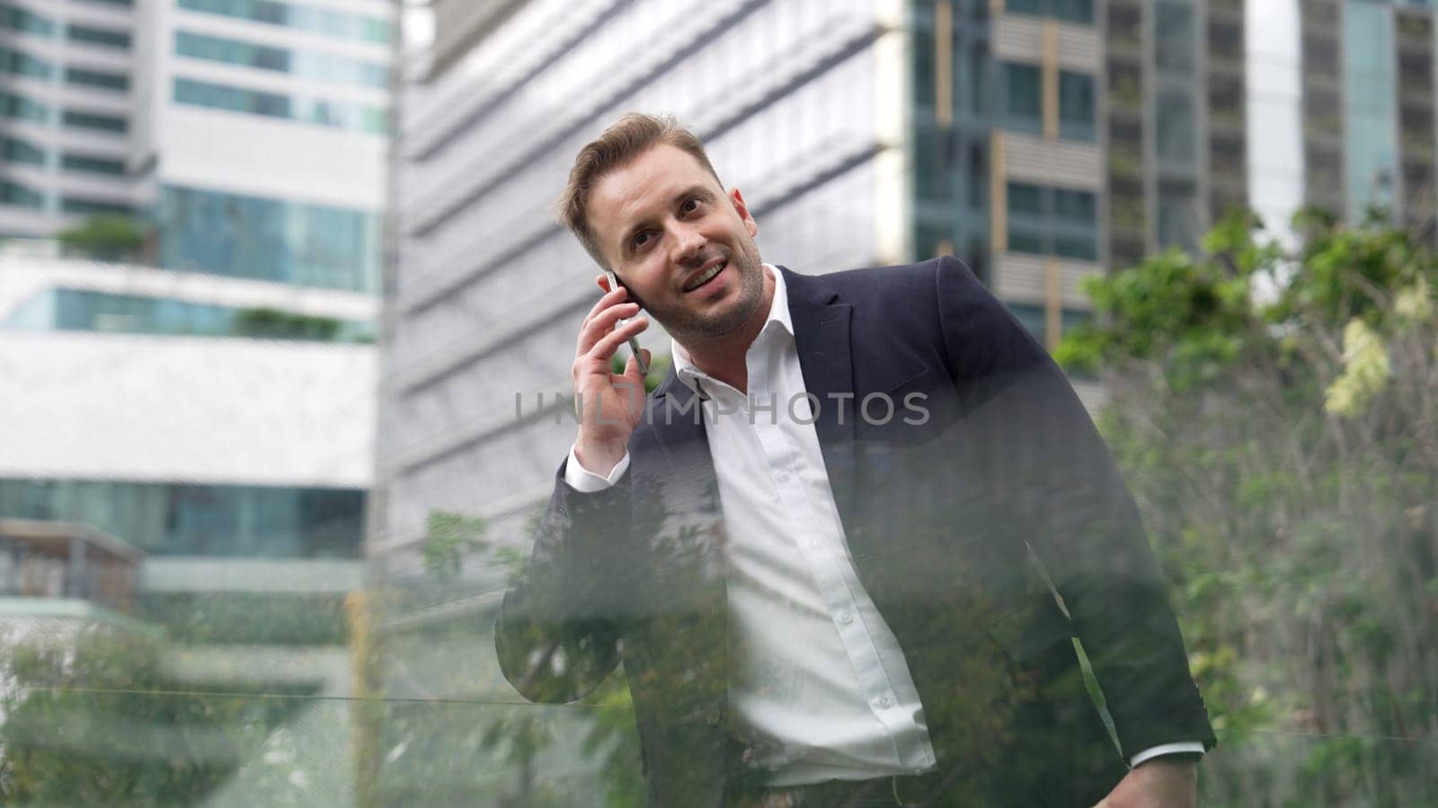 Businessman standing at rooftop while talking with team by using phone. Urbane by biancoblue